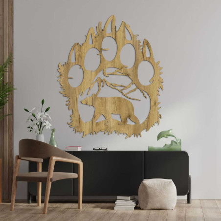 Ručne vyrezávaná dekorácia znázorňujúca medveďa kráčajúceho pod horským masívom.